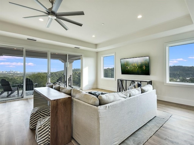 living area featuring light wood-style floors, plenty of natural light, visible vents, and baseboards