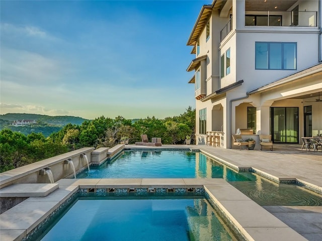 outdoor pool featuring an outdoor bar, a mountain view, a patio, and an in ground hot tub