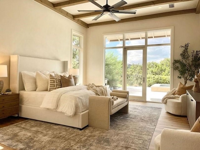 bedroom featuring access to outside, beam ceiling, wood finished floors, and multiple windows