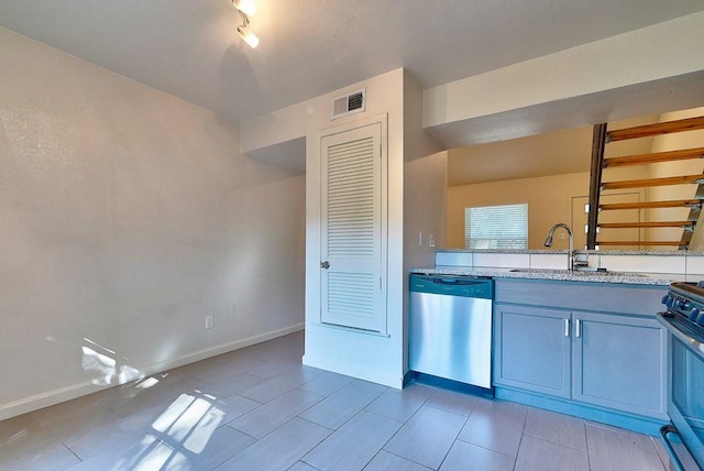 3465 Willowrun Dr, Austin, TX 78704 - kitchen with stainless steel appliances, a sink, baseboards, light stone counters, and blue cabinetry