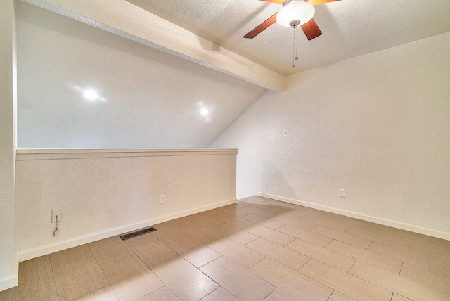 additional living space with ceiling fan and vaulted ceiling with beams