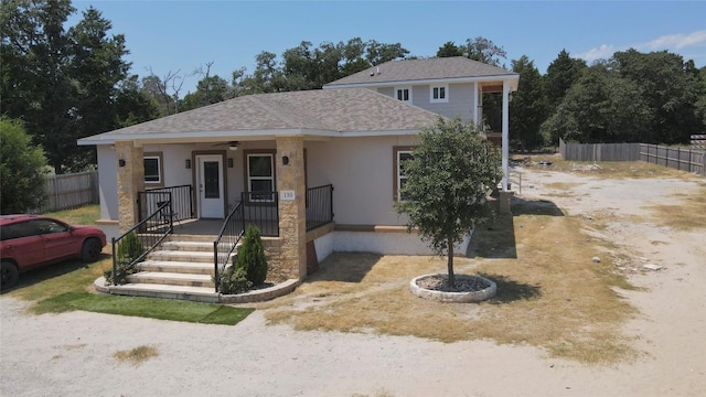 view of front of property featuring a ceiling fan, roof with shingles, fence, a porch, and stucco siding