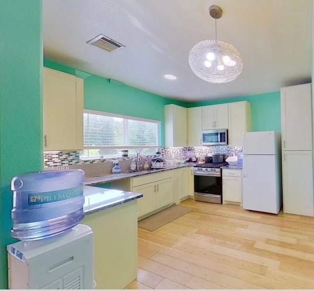 kitchen featuring appliances with stainless steel finishes, visible vents, backsplash, and light wood finished floors