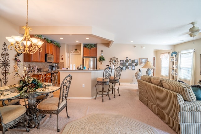 carpeted dining room featuring ceiling fan with notable chandelier