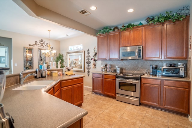 kitchen featuring appliances with stainless steel finishes, an inviting chandelier, sink, light tile patterned flooring, and hanging light fixtures