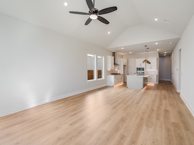 unfurnished living room featuring ceiling fan, light hardwood / wood-style floors, and vaulted ceiling