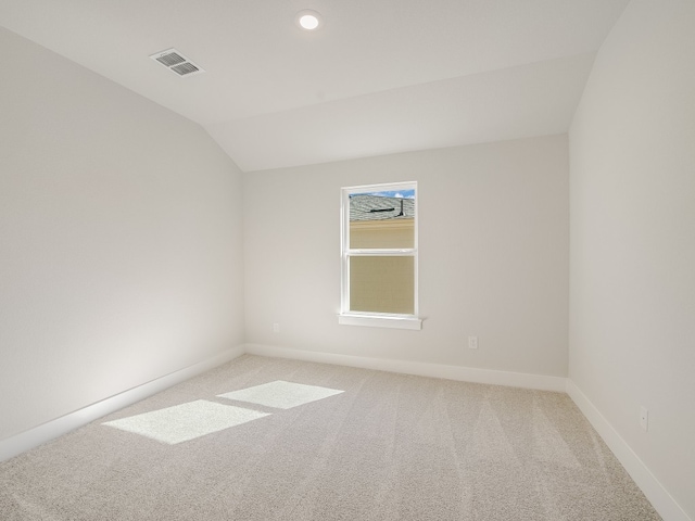 carpeted empty room with lofted ceiling