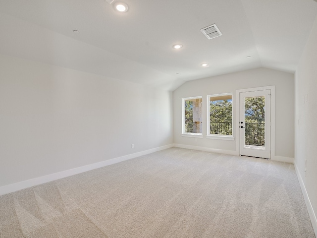 spare room featuring light carpet and vaulted ceiling