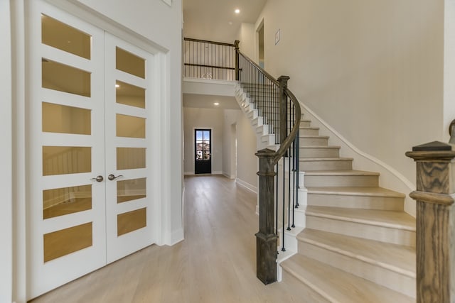 stairway with hardwood / wood-style flooring, a high ceiling, and french doors