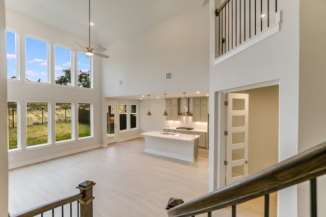 interior space with ceiling fan, a towering ceiling, light hardwood / wood-style flooring, and sink