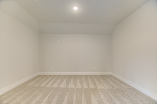 carpeted spare room with vaulted ceiling