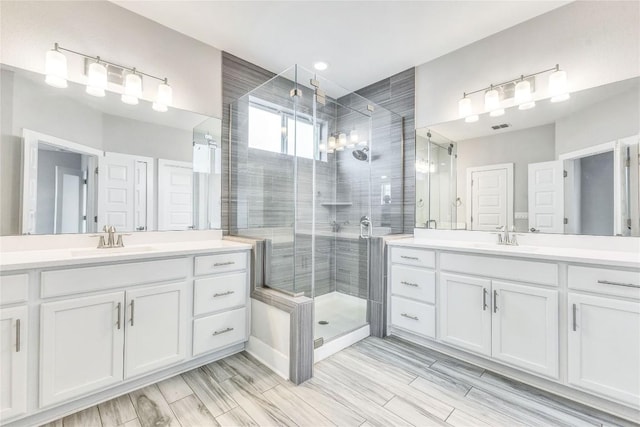 2016 Dinsdale Ln, Austin, TX 78741 - bathroom featuring a stall shower, two vanities, and wood tiled floors