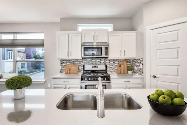 kitchen with stainless steel appliances, backsplash, and white cabinetry