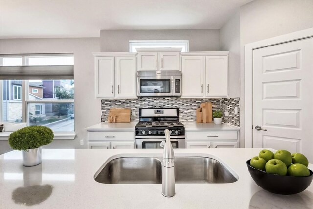 2016 Dinsdale Ln, Austin, TX 78741 - kitchen with stainless steel appliances, light countertops, white cabinets, and backsplash