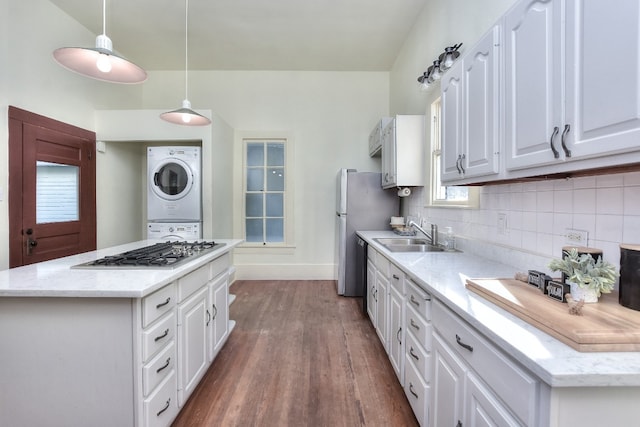 kitchen featuring a sink, white cabinetry, stacked washer / drying machine, appliances with stainless steel finishes, and tasteful backsplash