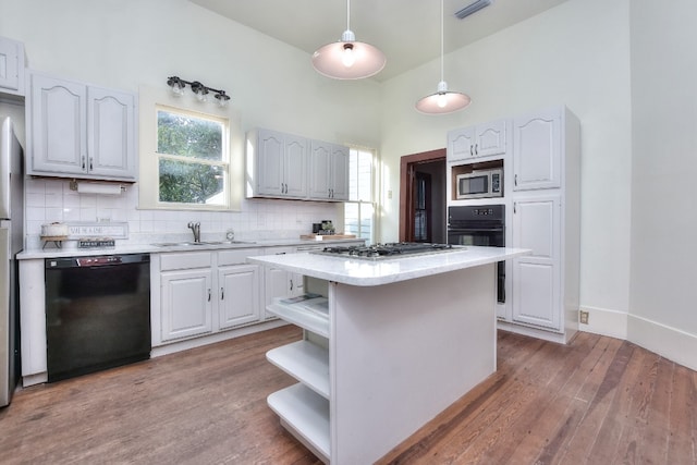 kitchen with decorative backsplash, a center island, black appliances, open shelves, and a sink