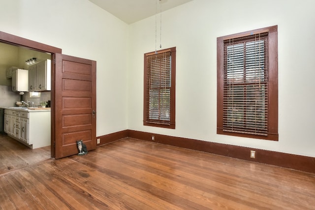 unfurnished dining area featuring baseboards, a sink, and hardwood / wood-style floors