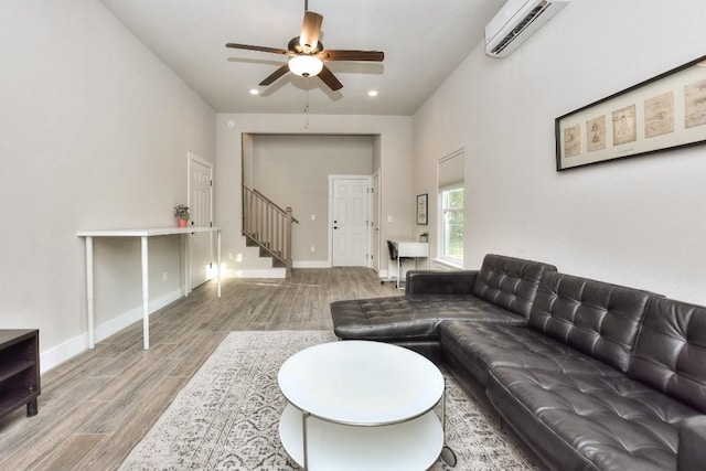 living area featuring baseboards, stairway, an AC wall unit, and wood finished floors