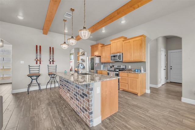 kitchen with light hardwood / wood-style flooring, stainless steel appliances, beamed ceiling, and light stone countertops