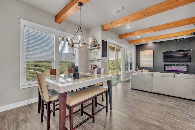 dining area featuring an inviting chandelier, beam ceiling, and light hardwood / wood-style floors