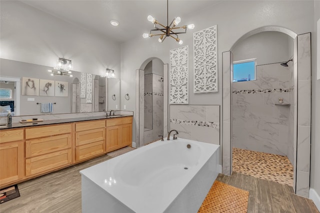 bathroom with plus walk in shower, hardwood / wood-style floors, a chandelier, and vanity