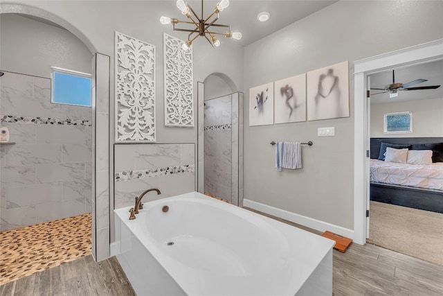 bathroom with ceiling fan with notable chandelier, hardwood / wood-style floors, and plus walk in shower