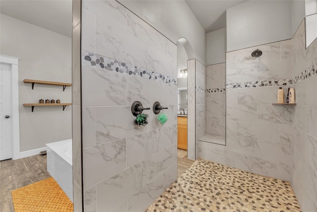 bathroom with a tile shower and wood-type flooring