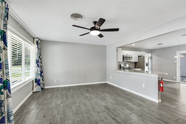 unfurnished living room featuring ceiling fan, sink, and hardwood / wood-style floors