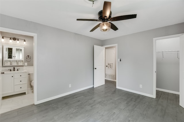 unfurnished bedroom featuring light wood-type flooring, sink, a closet, ceiling fan, and connected bathroom