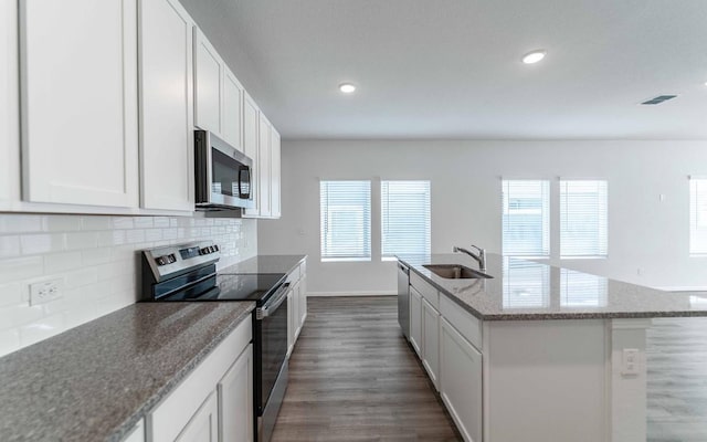 kitchen featuring sink, white cabinets, stainless steel appliances, and a center island with sink