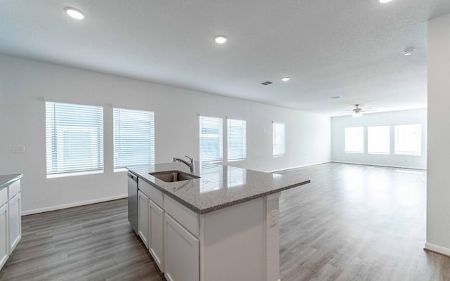 kitchen featuring a center island with sink, dishwasher, white cabinets, and sink