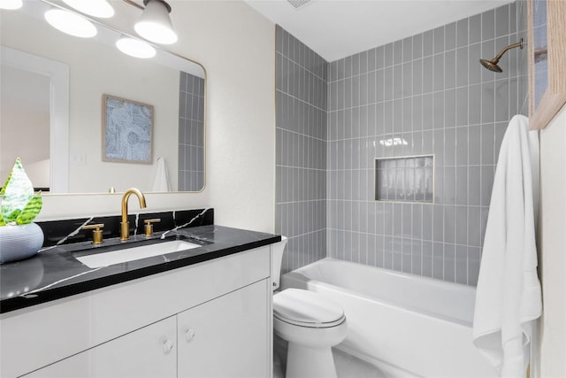 full bathroom with vanity, tiled shower / bath combo, and toilet