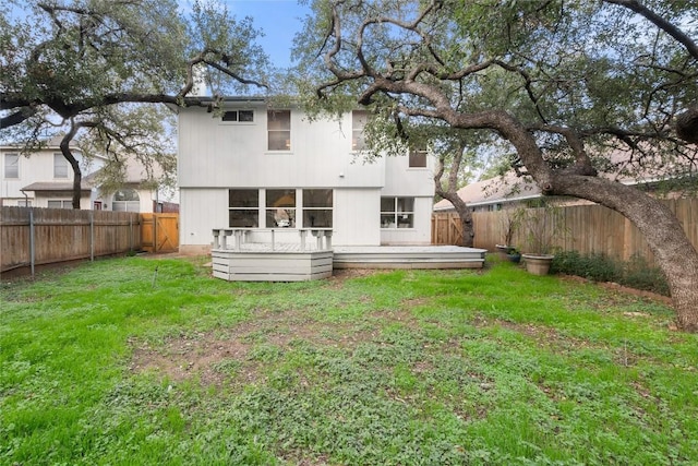 rear view of house featuring a lawn and a wooden deck