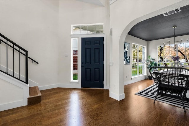 entrance foyer with a textured ceiling, an inviting chandelier, and dark wood-type flooring