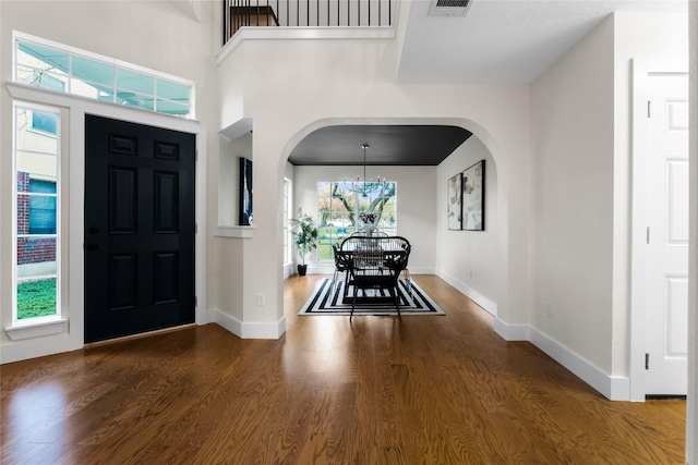 foyer entrance with a chandelier, a high ceiling, and dark wood-type flooring