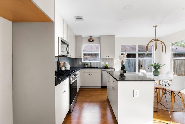 kitchen with pendant lighting, backsplash, dark hardwood / wood-style floors, appliances with stainless steel finishes, and white cabinetry