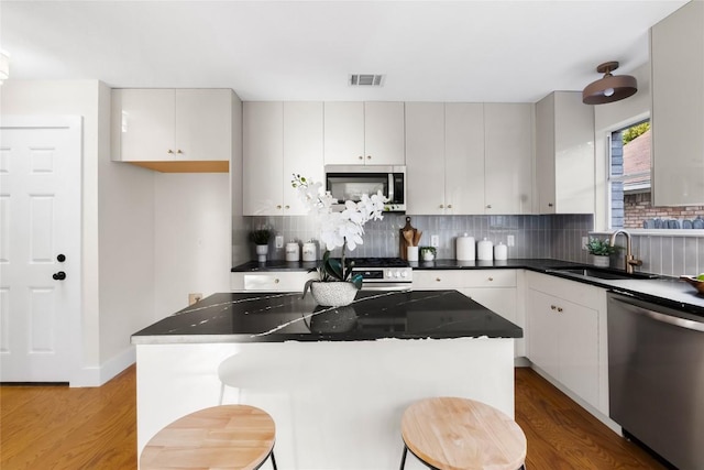 kitchen featuring appliances with stainless steel finishes, a center island, white cabinetry, and sink