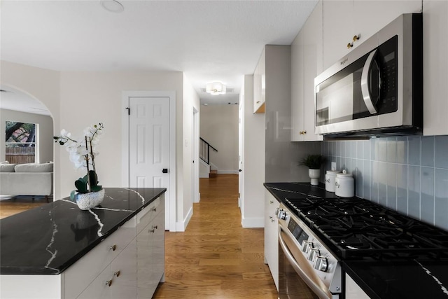 kitchen with white cabinets, hardwood / wood-style floors, and appliances with stainless steel finishes