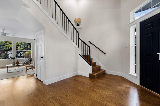 foyer with ceiling fan, wood-type flooring, and a high ceiling