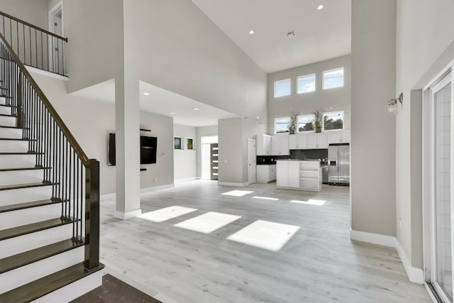 entryway featuring a towering ceiling and light wood-type flooring