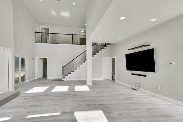 unfurnished living room with a towering ceiling and light hardwood / wood-style floors