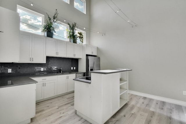 kitchen featuring a high ceiling, a center island, decorative backsplash, and light hardwood / wood-style flooring