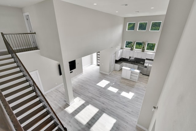 living room featuring a towering ceiling and light hardwood / wood-style floors