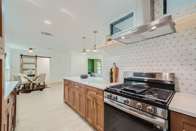 kitchen with wall chimney range hood, decorative light fixtures, and gas stove