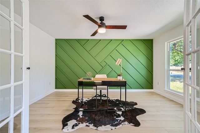 home office with french doors, a healthy amount of sunlight, and light hardwood / wood-style flooring