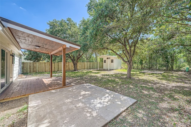 view of yard with a storage unit, a wooden deck, ceiling fan, and a patio area