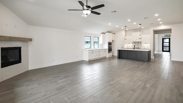 unfurnished living room featuring ceiling fan, sink, lofted ceiling, and a fireplace