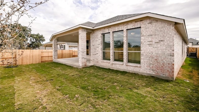 back of house with a lawn and a patio