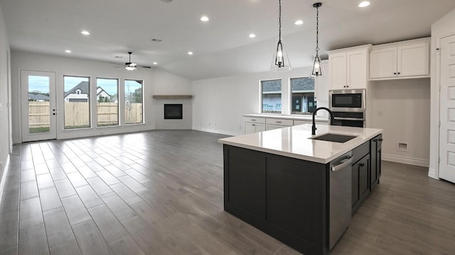 kitchen with a center island with sink, sink, ceiling fan, white cabinetry, and stainless steel appliances