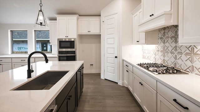 kitchen featuring pendant lighting, sink, dark hardwood / wood-style flooring, white cabinetry, and stainless steel appliances